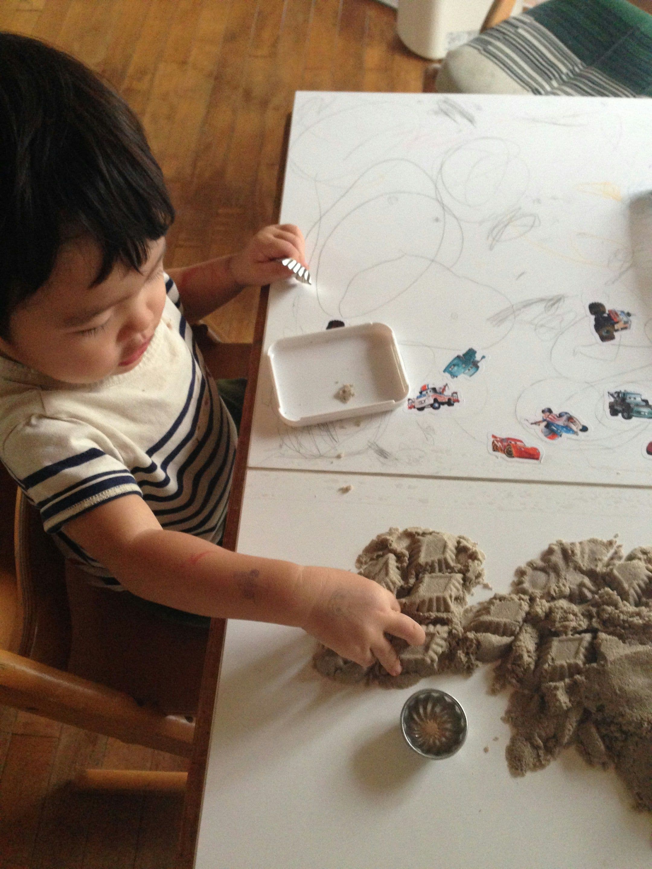 a little child is playing with sand on a table